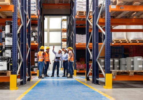 Forperson talking to a group of employees in a meeting at a distribution warehouse and pointing away